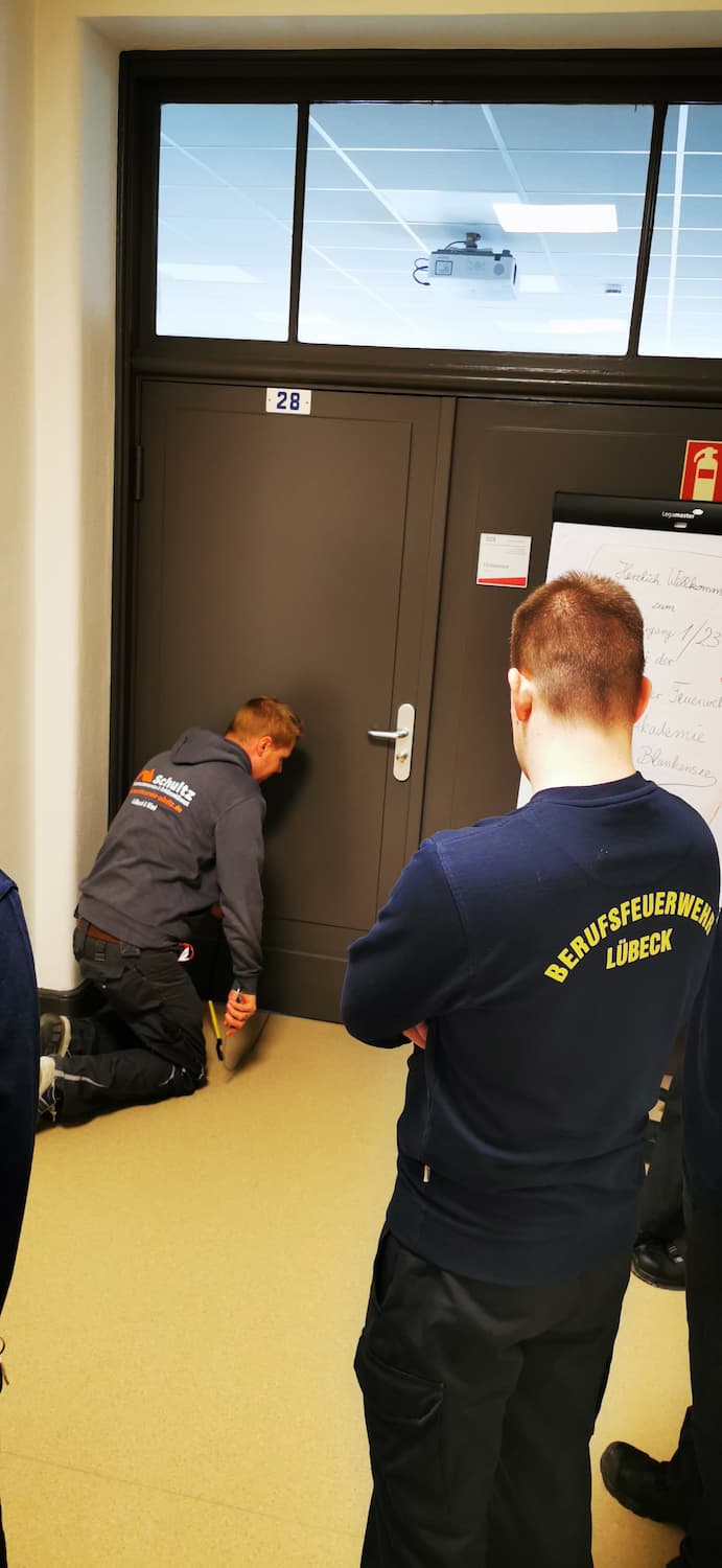 Ein Mitarbeiter vom Schlüsseldienst Schultz zeigt den Lehrgangs-Teilnehmer die Vorgehensweise beim Tür öffnen.